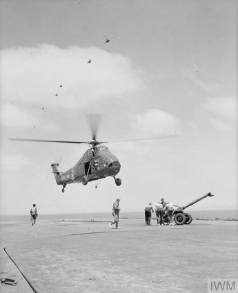 A Wessex helicopter prepares to lift a Mobat (mobile 105 mm anti-tank gun) from HMS BULWARK.